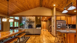 A spacious kitchen with wooden cabinets, a stone fireplace, and a large island with stools.
