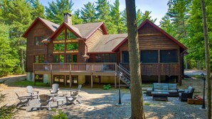 A log cabin with a balcony, outdoor seating, and a staircase leading to the upper level.