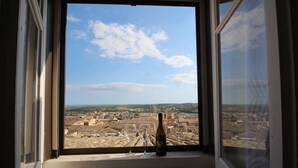 A window with a view of a cityscape, a bottle, and a wine glass on the windowsill. - Noto Da Quassù Relax B&B (Noto)