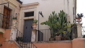 A building with a grey door, a large cactus, and potted plants. - Noto Da Quassù Relax B&B (Noto)