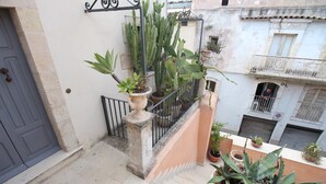 A balcony with potted plants, a metal railing, and a door. - Noto Da Quassù Relax B&B (Noto)