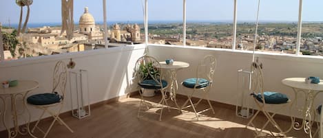 Un balcón con vistas a un casco antiguo, que incluye una cúpula destacada y edificios de tejas a la vista.