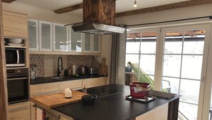 A modern kitchen with wooden cabinetry, a black countertop, and a large window providing a view of the outdoors.