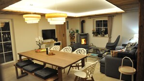 A cozy living room with a fireplace, a dining area with a wooden table and chairs, and a comfortable seating area with a sofa and armchairs.