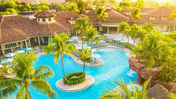 A resort with a central swimming pool, palm trees, and lounge areas. - Enjoy Players Club Access in this Luxurious Naples Golf Course Home.   (Naples)