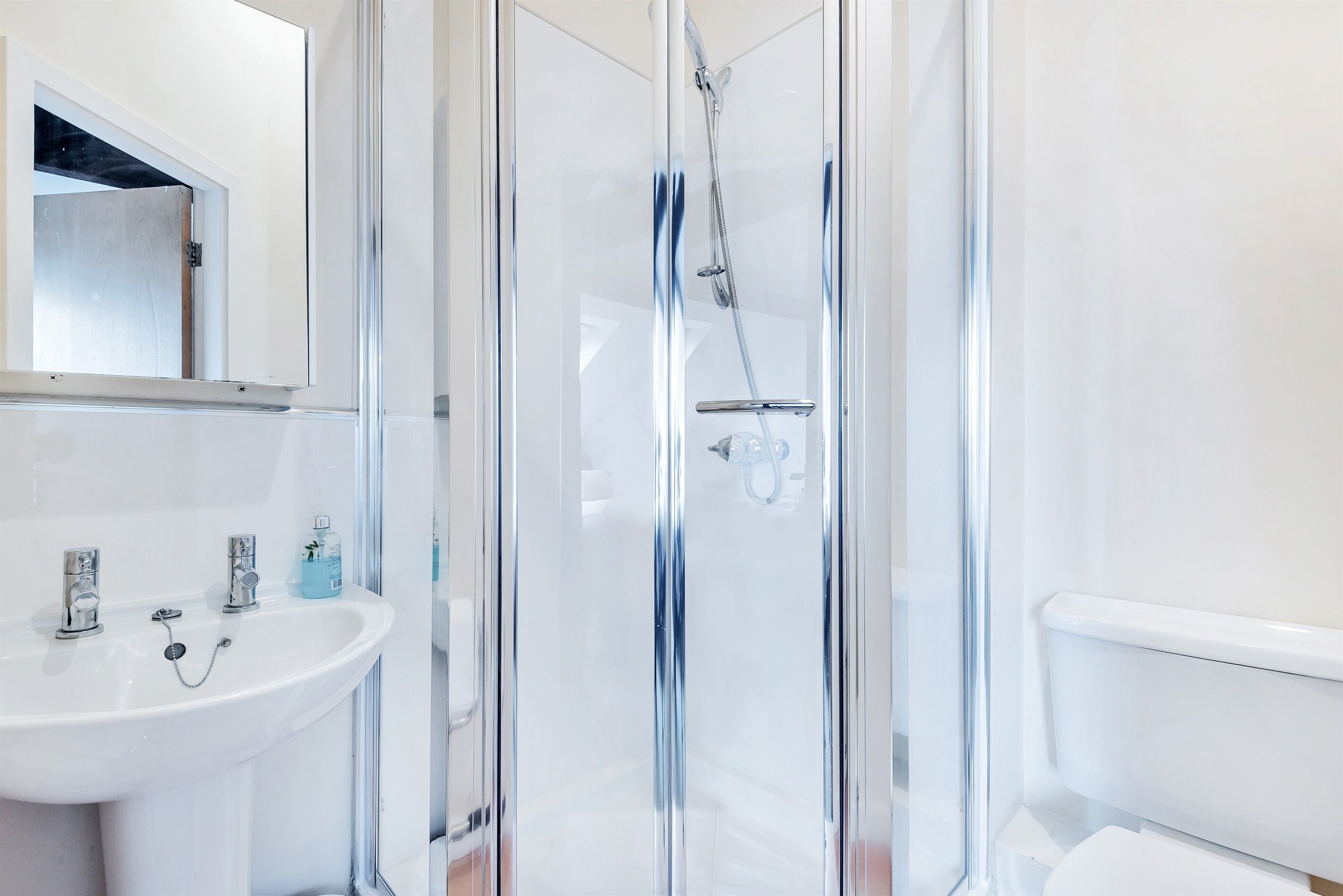 Une salle de bain moderne avec une douche à parois de verre, un lavabo blanc et des toilettes.