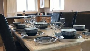 A dining area with a wooden table set for six, surrounded by black chairs. - Woodlands Cottage - Rural Retreat - Near York (North Duffield)