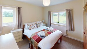 A bedroom with a bed, bedside tables, a window, and a view of the outdoors. - Woodlands Cottage - Rural Retreat - Near York (North Duffield)