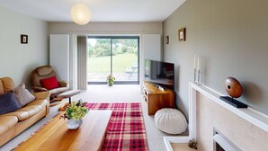 A modern living room with a leather sofa, a wooden coffee table, a flat-screen TV, and a fireplace. - Woodlands Cottage - Rural Retreat - Near York (North Duffield)