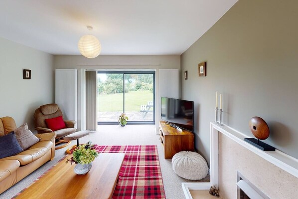 A modern living room with a leather sofa, a wooden coffee table, a flat-screen TV, and a fireplace. - Woodlands Cottage - Rural Retreat - Near York (North Duffield)
