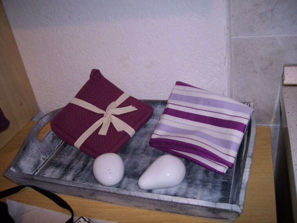 A tray with a folded purple towel, a striped towel, and two white stones.