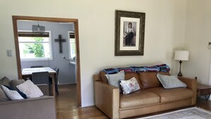 A living room with a brown leather sofa, a patterned rug, and a framed picture on the wall. - Spacious & gracious (Hamilton)
