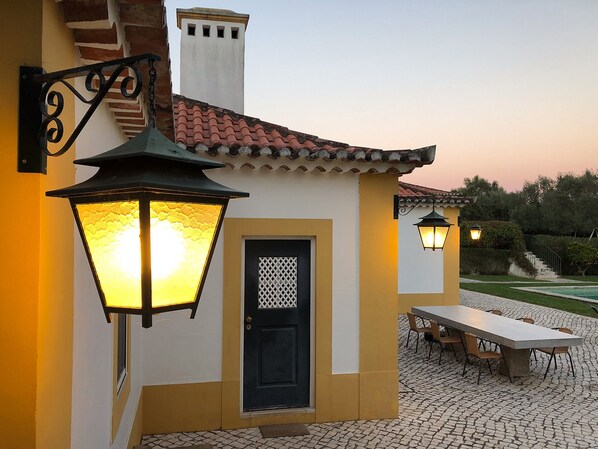A building with a tiled roof, a door with a lattice design, and outdoor seating.