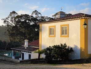 A building with two windows, a yellow and white facade, and a red-tiled roof. - Quinta do Pé Descalço: typical Portuguese house with pool for 14, Sintra (Sintra)