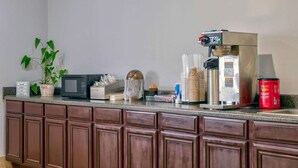 A kitchen counter with a coffee machine, microwave, and a potted plant. - Motel 6 Byron, GA (Byron)