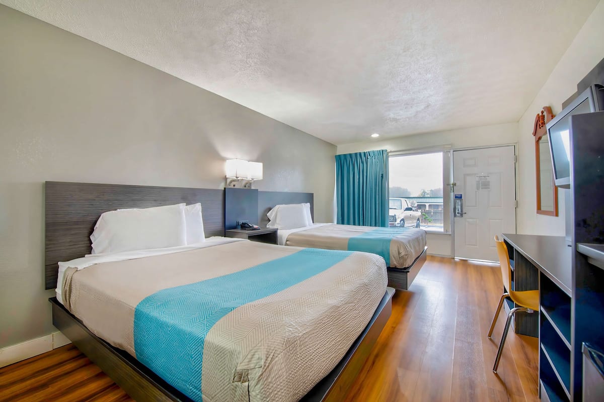 Ein Hotelzimmer mit zwei Betten, einem Schreibtisch und einem Fernseher.