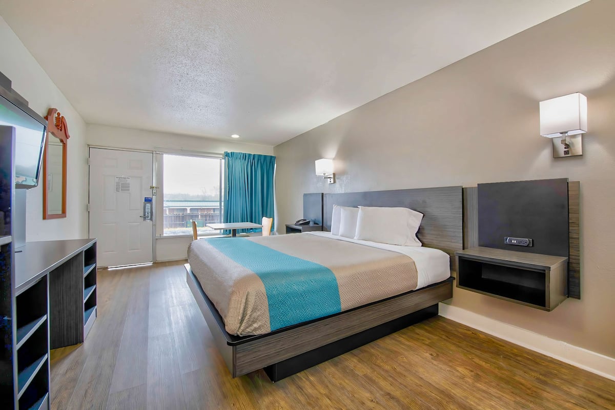 Ein Hotelzimmer mit Bett, Schreibtisch, Fernseher und einem Fenster mit Vorhängen.