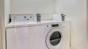 A front-loading washing machine with a control panel, a digital display, and a small storage compartment. - Motel 6 Byron, GA (Byron)