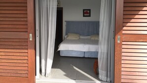 A bedroom with a bed, curtains, and a picture on the wall.