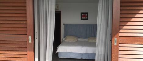 A bedroom with a bed, curtains, and a picture on the wall.