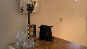 Ein Kaffee-Bereich mit einem Schild mit der Aufschrift "CAFE 5", einer Kaffeemaschine, einem Korb und einem Glasbehälter auf einem Holztisch.