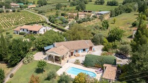 Una villa con piscina, rodeada de exuberante vegetación y viñedos.