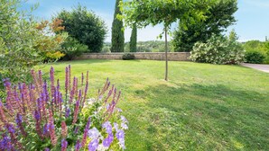 Un jardín cuidado con diversas plantas y un muro de piedra al fondo.