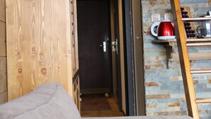 Un mur en bois avec une échelle et une bouilloire rouge posée sur une étagère.