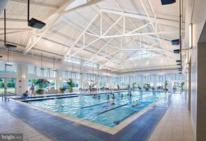 En indendørs swimmingpool med højt til loftet og store vinduer.