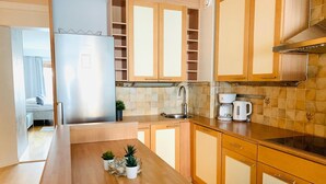 Una cocina moderna con armarios de madera, un refrigerador de acero inoxidable y una cafetera.