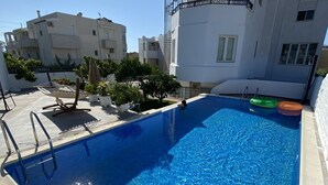 Ein Dachpool mit klarem, blauem Wasser, umgeben von weißen Gebäuden und Kübelpflanzen.