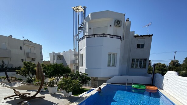 Ein rechteckiger Pool mit einer Metallleiter an einer Seite, umgeben von einer gefliesten Terrasse.