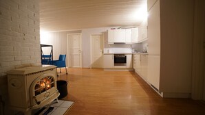 Una cocina moderna con armarios blancos, una estufa y una zona de comedor con una silla azul.