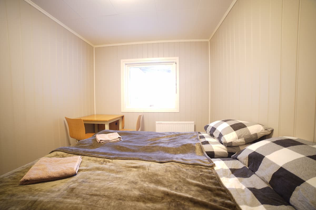 Um quarto com uma cama, uma escrivaninha e uma janela.
