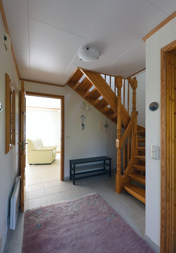 A spacious living area with a wooden staircase, a bench, and a sofa.