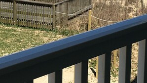 Een uitzicht op het strand met een houten hek en grasduinen.