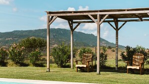 Ein hölzerner Pergola über einem Swimmingpool mit zwei Adirondack-Stühlen und Blick auf Berge.