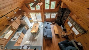 Une cabane comprenant une cuisine, un coin repas et un salon, avec des murs en bois et un plafond en pente.