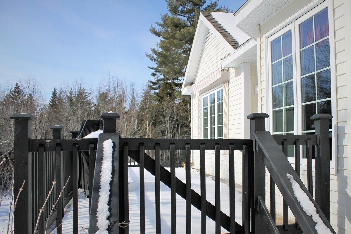 A house with a snow-covered deck and a black metal gate.
