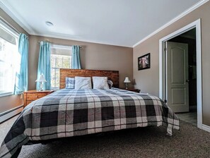 A bedroom with a bed, a nightstand, a lamp, and a door.