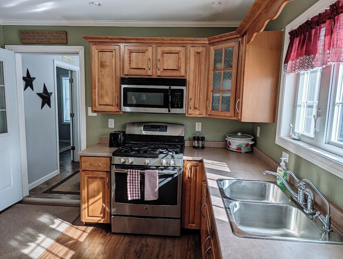 A kitchen with wooden cabinets, a microwave, a stove, and a sink.