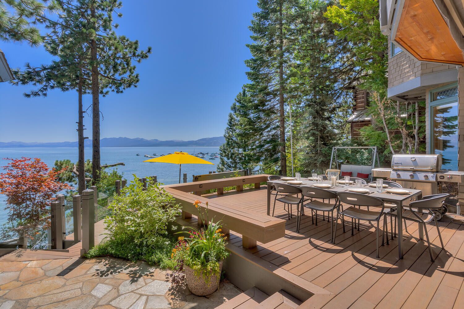 Une terrasse avec une table et des chaises, un barbecue et une vue sur le lac.