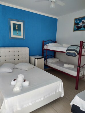 A hotel room with a single bed, a bunk bed, a small desk, and a ceiling fan. - Pousada Iza I (Guarujá)