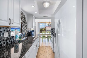 Une cuisine moderne avec des meubles blancs, un plan de travail noir et un pare-feu en carrelage.