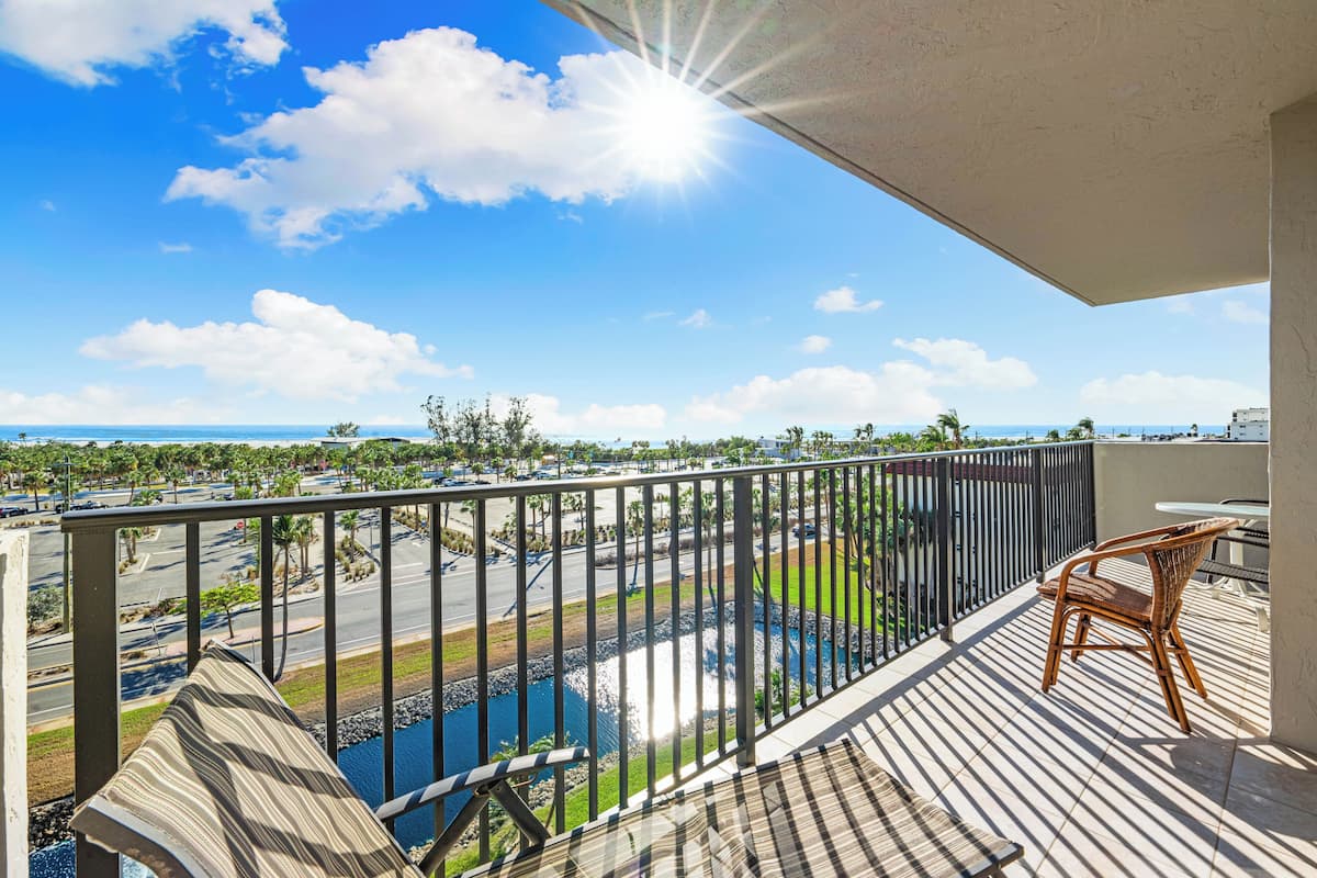 Un balcon donnant sur une route, un plan d’eau et une côte lointaine.