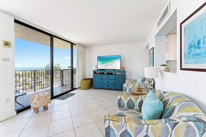 Un salon moderne avec une grande télévision, un canapé et un balcon offrant une belle vue.