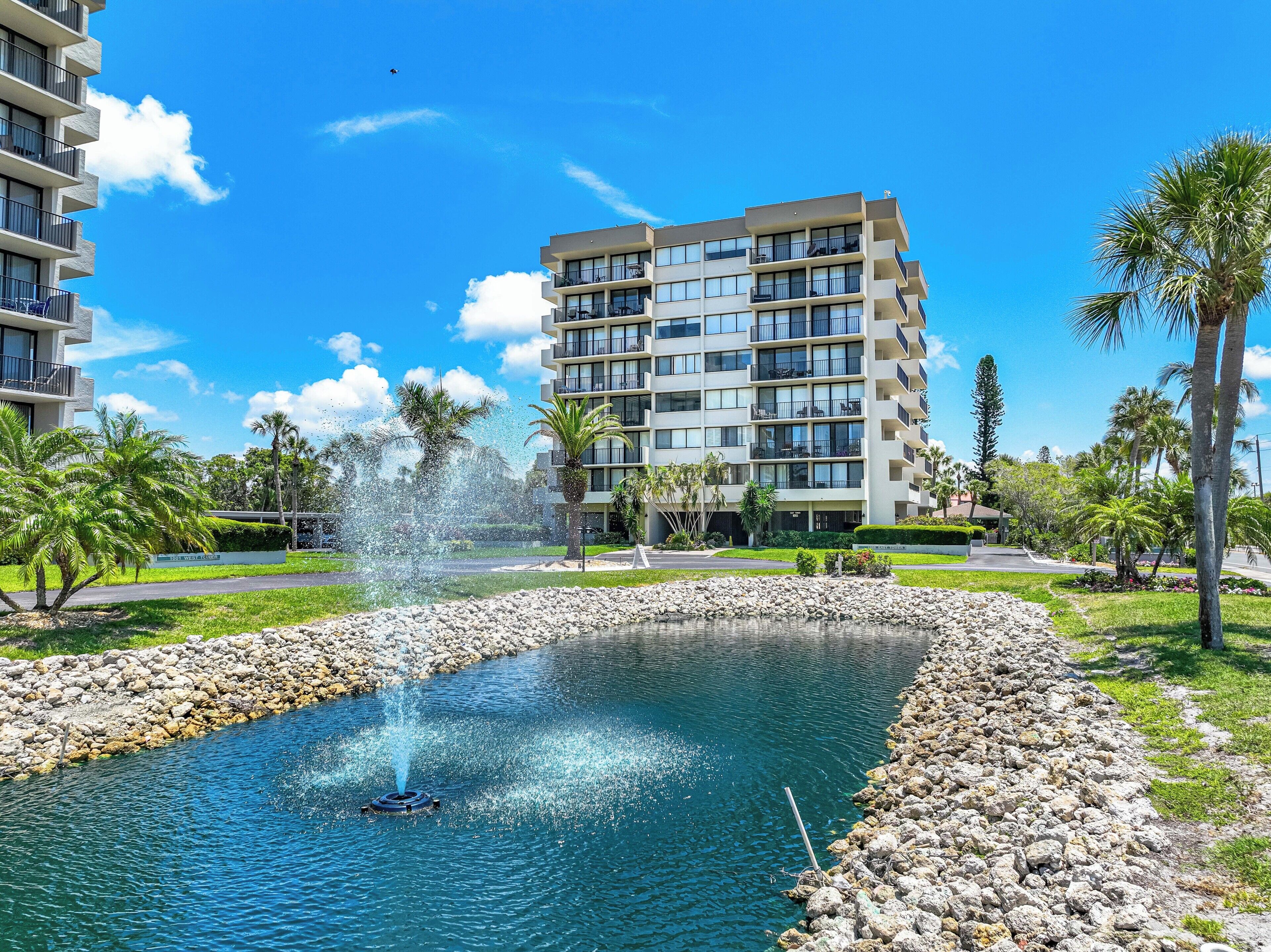Un hotel moderno con numerosi balconi, una fontana centrale e vegetazione circostante.