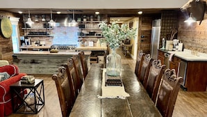 Une cuisine rustique avec une longue table en bois, des chaises et un vase central.