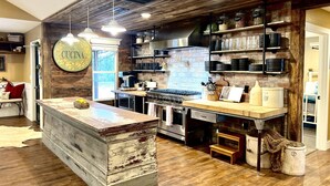 Une cuisine rustique avec des poutres en bois, un îlot central et un mur de fond en briques.