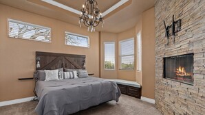A bedroom with a bed, a bench, a fireplace, and a chandelier. - Lakeview villa- spacious Mediterranean home with amazing lake views! (Canyon Lake)